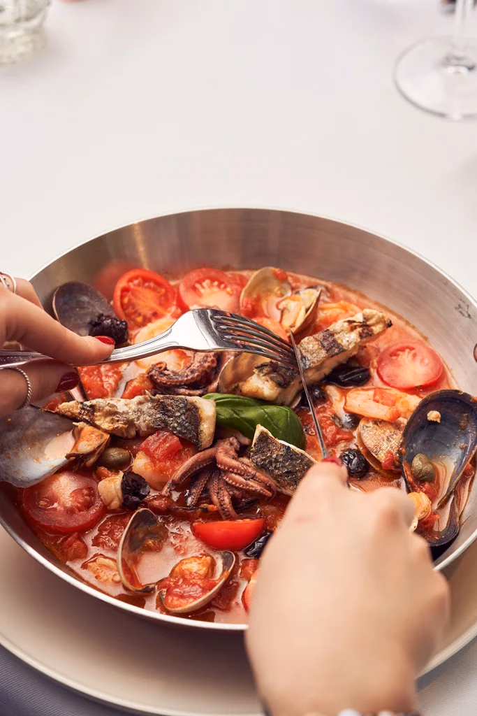Vento Italiano restoran yemek fotoğrafı, tavada domates soslu deniz mahsulleri ve balık, çatalla servis anı, Ankara yemek fotoğrafçısı Şems Erik