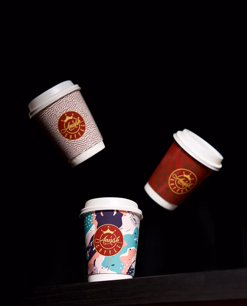 Anisah Coffee marka baskılı üç adet karton kahve bardağı, siyah fonda havada süzülen dinamik kompozisyon, Ankara ürün fotoğrafçısı Şems Erik