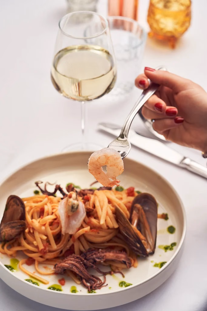 Vento Italiano restoran yemek fotoğrafı, çatalla karides alınan deniz mahsullü makarna sahnesi, şarap kadehi eşliğinde, Ankara yemek fotoğrafçısı Şems Erik